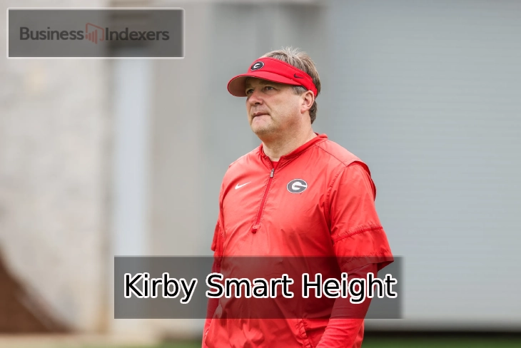 Kirby Smart Height, Georgia Bulldogs head coach, standing on a football field wearing a red jacket and visor.