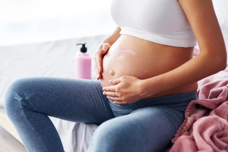 Pregnant woman using natural skincare products for a safe and glowing pregnancy skincare routine.