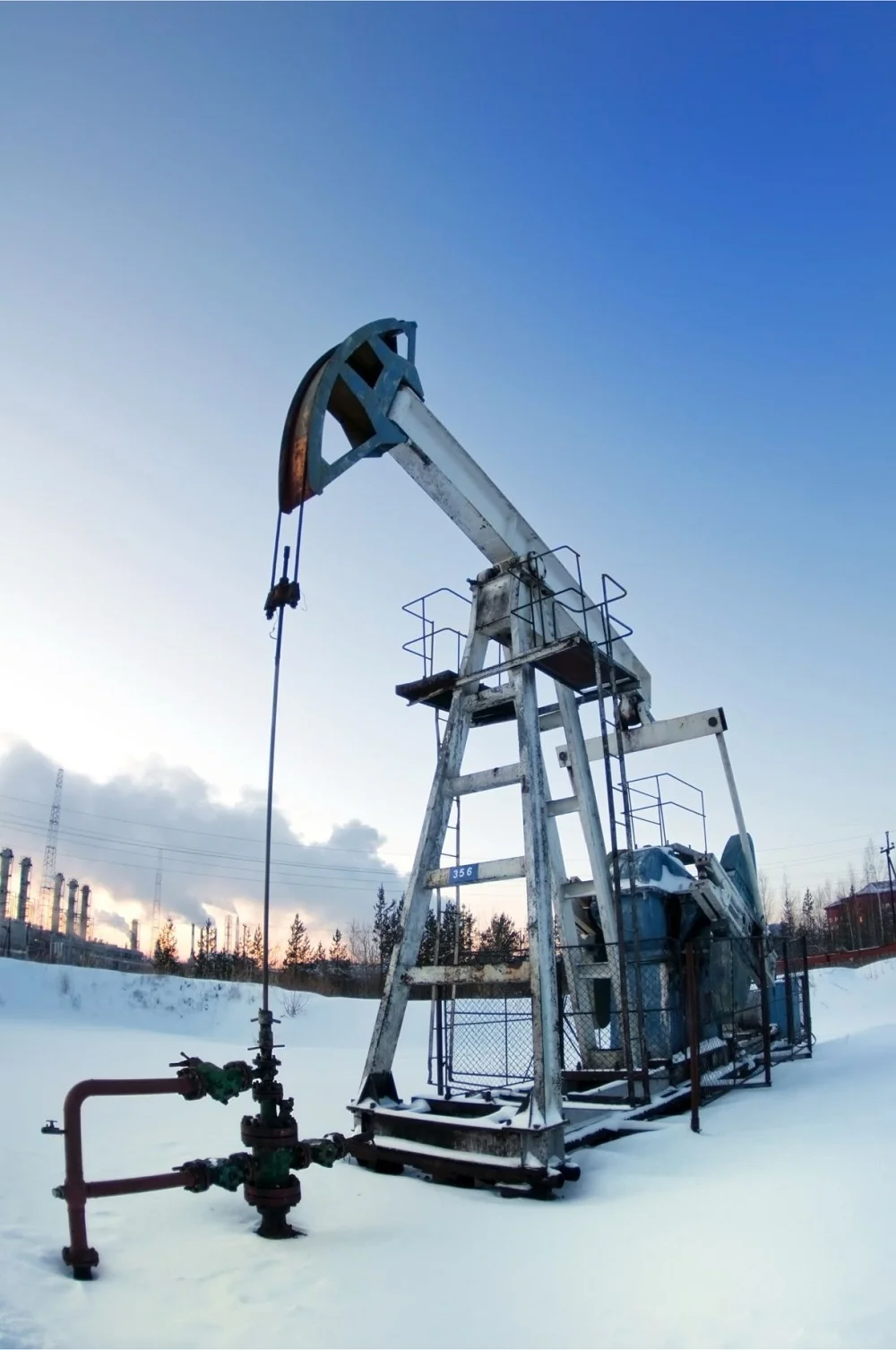 Oil pumpjack at a Del Mar Energy Inc. site in winter, showing energy extraction equipment under a clear sky